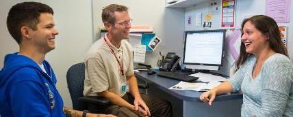 Two students sit with an academic advisor.